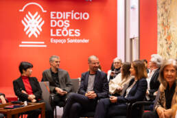 Participantes sentados no espaço do evento, em momento de conversa e descontração antes ou após o debate no Edifício dos Leões.
