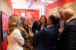 Grupo de pessoas em conversa animada próximo a uma tela digital, durante momento de networking no evento do Edifício dos Leões.